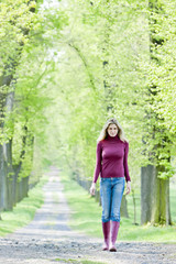 Fototapeta premium woman wearing rubber boots in spring alley