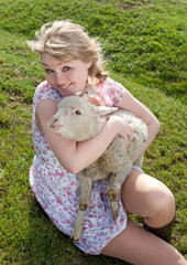 Young pretty cheerful blond woman with lamb on a countryside