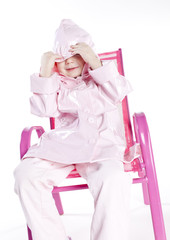 little girl wearing raincoat sitting on chair