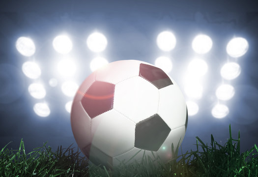 Soccer ball on grass field with spotlights