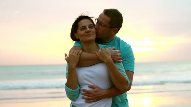Young happy couple hugging at the beach on sunset