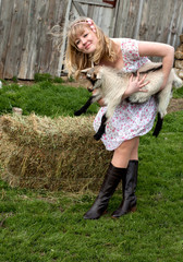 Young pretty cheerful blond woman with goat on a countryside