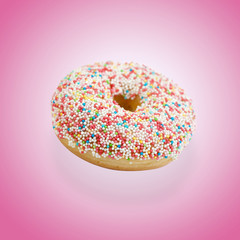 Donut mit bunten Zuckerperlen vor rosa Hintergrund