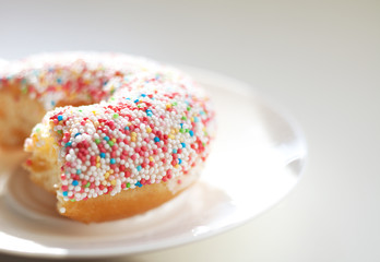 Angebissener Donut mit bunten Zuckerperlen auf einem Teller