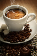 A small cup of strong coffee on the brown background