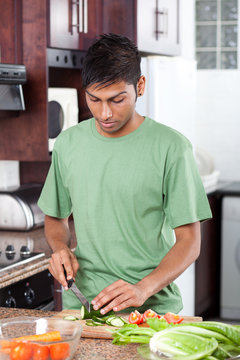 Young Casual Indian Man Cooking In Kitchen