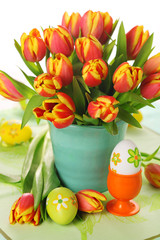 Beautiful bouquet of tulips in vase with Easter eggs.