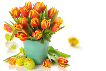 Beautiful bouquet of tulips in vase with Easter eggs on white ba