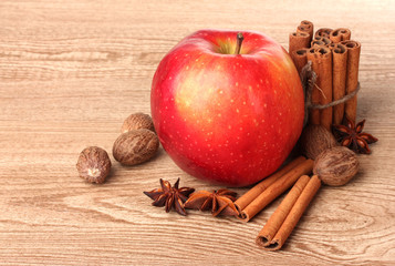 Cinnamon sticks,red apple, nutmeg,and anise on wooden table