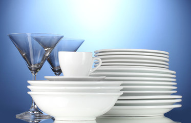empty bowls, plates, cups and glasses on blue background
