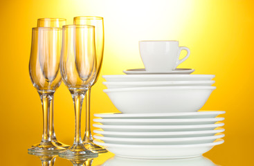 empty bowls, plates, cups and glasses on yellow background