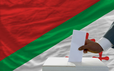 man voting on elections in front of national flag of katanga