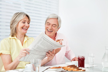 Lachende Senioren lesen Zeitung