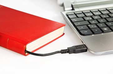 Buch mit Kabel and Computer angeschlossen als Symbol für Ebooks