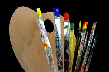Paintbrushes and palette on black background.