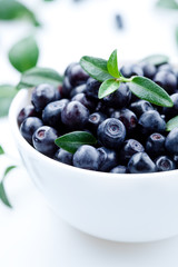 Blueberries with leaves in plate. isolated on white background