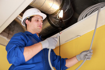 Electrician repairing ceiling wiring
