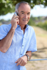 65 years old man at phone in front of a village