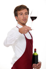 Sommelier holding up a glass of wine - obrazy, fototapety, plakaty