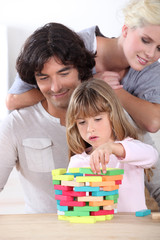 parents looking her daughter playing with blocks