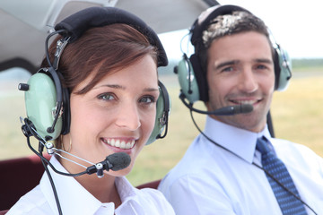 Man and woman wearing headsets in the open cockpit