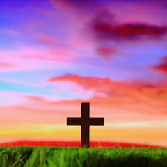 cross silhouette on grass with sunset background