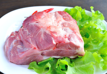 Raw pork on the plate with vegetables.