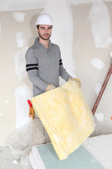 Worker handling square of insulation