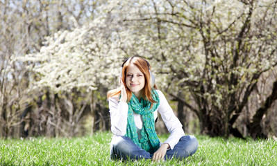 Redhead girl with headphone in the park.