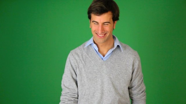 Young man talking to camera on green background