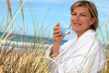 Woman drinking a glass of water by the seaside