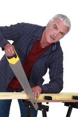 Elderly handyman sawing wood