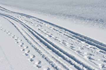 Tire tracks and footsteps in white snow