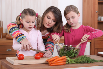 Mother teaching her daughters how to cook.