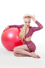 Young woman in modern attire posing with exercise ball