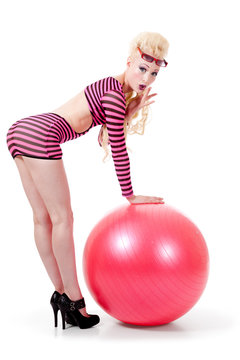 Young woman in modern attire posing with exercise ball
