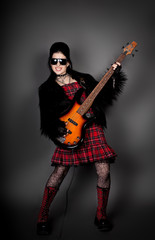 Fashion style photo of young rocked woman in studio  with guitar