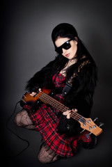 Fashion style photo of young rocked woman in studio  with guitar