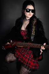 Fototapeta premium Fashion style photo of young rocked woman in studio with guitar