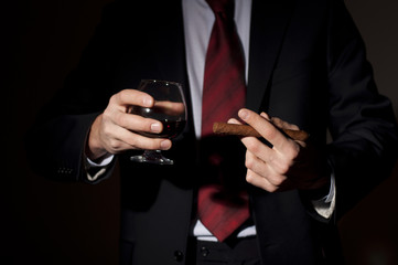 rich person, holds a cigar and whisky