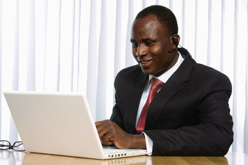 Portrait of an African American sitting on the desk with laptop