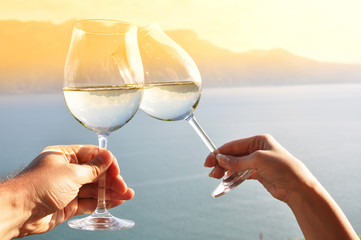 Two hands holding wineglases against Geneva lake, Switzerland - 39100355