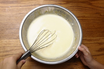 Child hands mixing some egg, milk, sugar,
