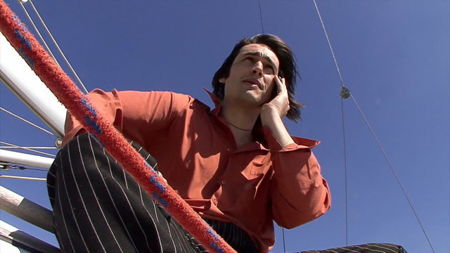 Man speaks on telephone on sailboat