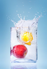 Apple and orange in water splashes