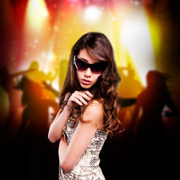 junge brünette Frau mit Sonnenbrille vor Party-Hintergrund