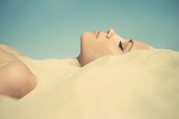 Fototapeta premium Beautiful lady buried in the sand