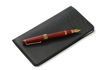 A ballpen on a closed leather checkbook