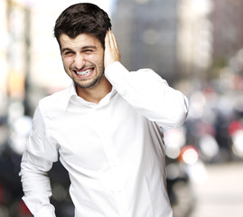 portrait of young man irritated hearing a loud at city
