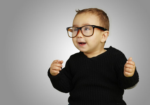 portrait of adorable kid wearing glasses and gesturing over grey